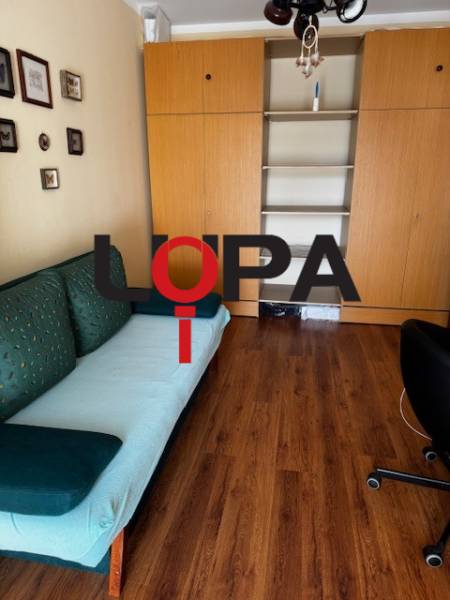 Szoba egy háromszobás lakásban fa dekor padlóval és beépített szekrényekkel.