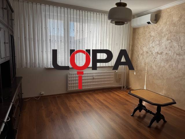 Szoba fa dekorációs padlóval és asztallal egy háromszobás lakásban.