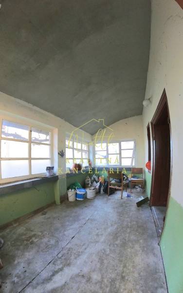 Családi ház belső tere régi ablakokkal és betonpadlóval.