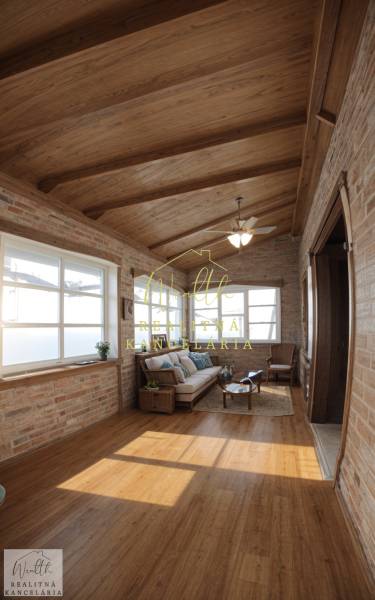Családi ház belső tere téglafalakkal, fa mintázatú padlóval és kényelmes ülőalkalmatosságokkal.