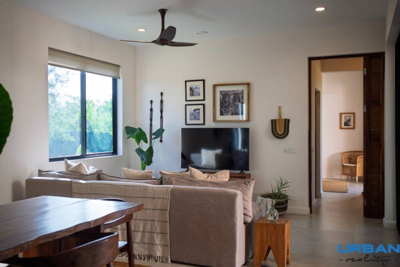 Belső tér kanapéval, televízióval és fa bútorokkal egy épülő házban.