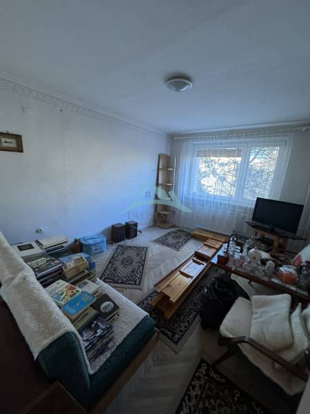 Nappali egy háromszobás lakásban fa dekor padlóval és bútorokkal.