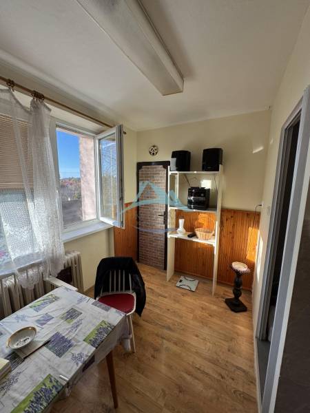 Ebédlő egy 3 szobás lakásban, fa dekoros padlóval és nyitott ablakkal.