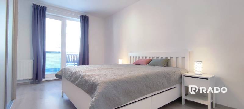 Hálószoba egy kétszobás lakásban világos bútorokkal és fa dekorációjú padlóval.