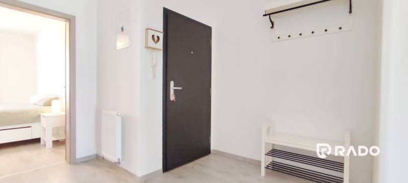 Előszoba világos falakkal és fa dekorációjú padlóval, amely a hálószobába vezet.