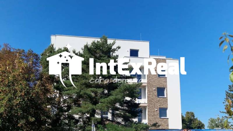 Az épület a Galántai Sport utcában, fákkal körülvéve, tiszta égbolttal a háttérben.