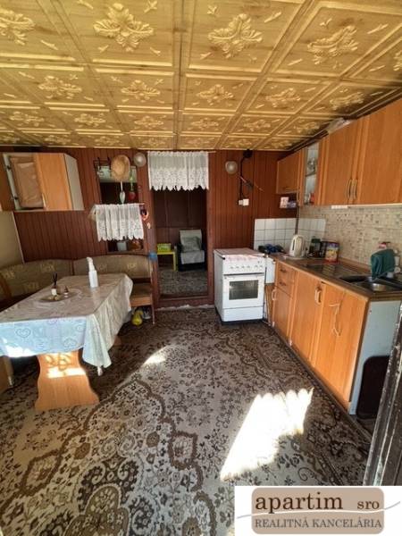 Konyha régi bútorokkal, fa mintázatú padló, látható étkező rész.