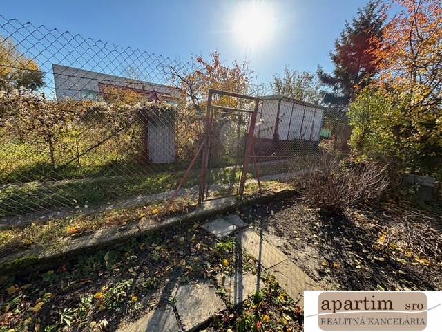 Középső utcai kertek Pozsony-Ružinovban kerítéssel és zöldterülettel.