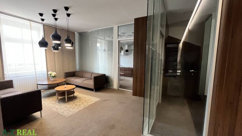 Irodák kanapékkal és dohányzóasztallal, fa mintázatú padló, üveg válaszfalak.