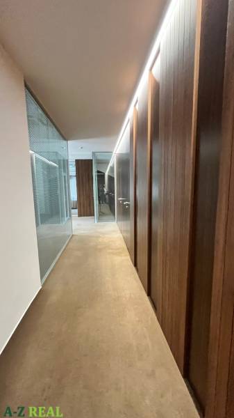 Irodák folyosója üveg válaszfalakkal, fa dekoros padlóval.