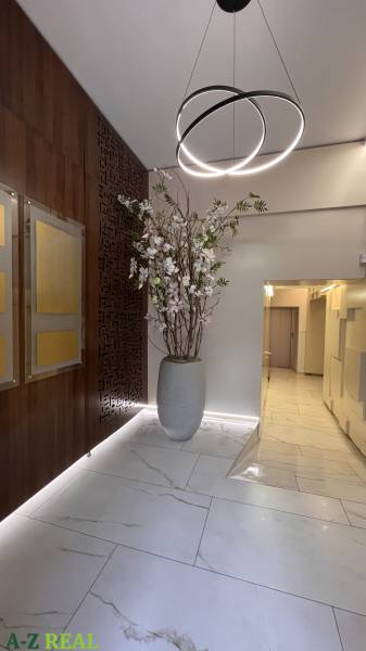 Irodák száraz virágokkal teli vázával, fa dekorációkkal és érdekes világítással a bejárat felett.