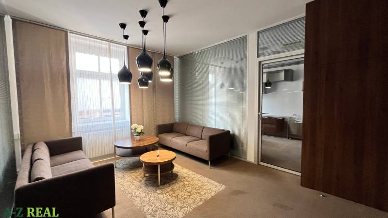 Irodák kényelmes kanapékkal, kerek asztallal és érdekes mennyezeti világítással.