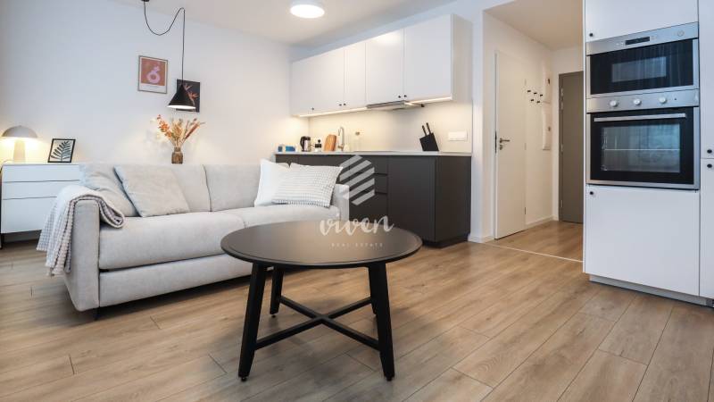 Nappali konyhasarokkal egy szobás lakásban, fa dekorációjú padlóval.