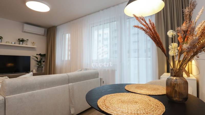 Egyszobás lakás nappalija kényelmes ülőhelyekkel és dekoratív elemekkel.