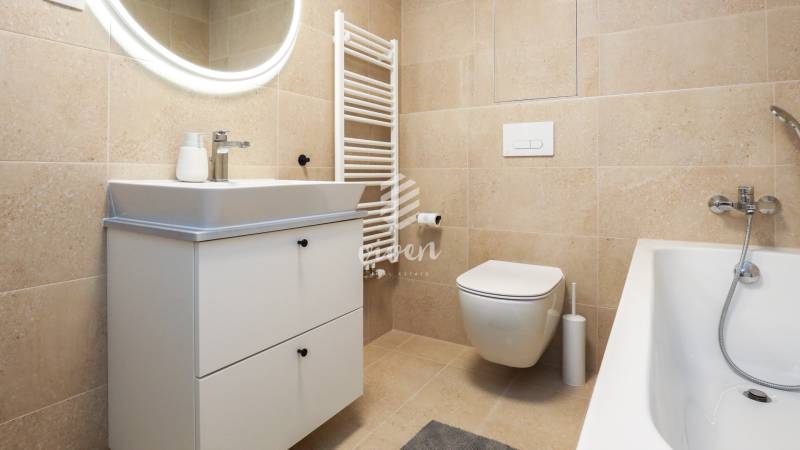 Fürdőszoba egy egyszobás lakásban mosdószekrénnyel, WC-vel és káddal.