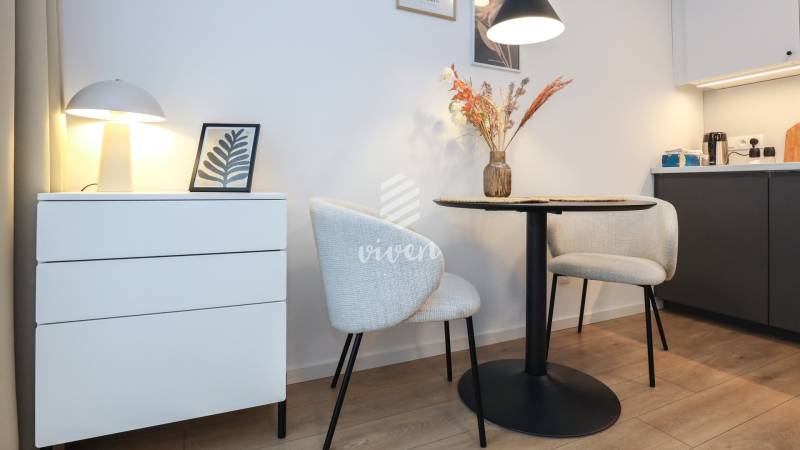 1 szobás lakás dekoratív székekkel, asztallal és lámpával, fa dekorációjú padlón.