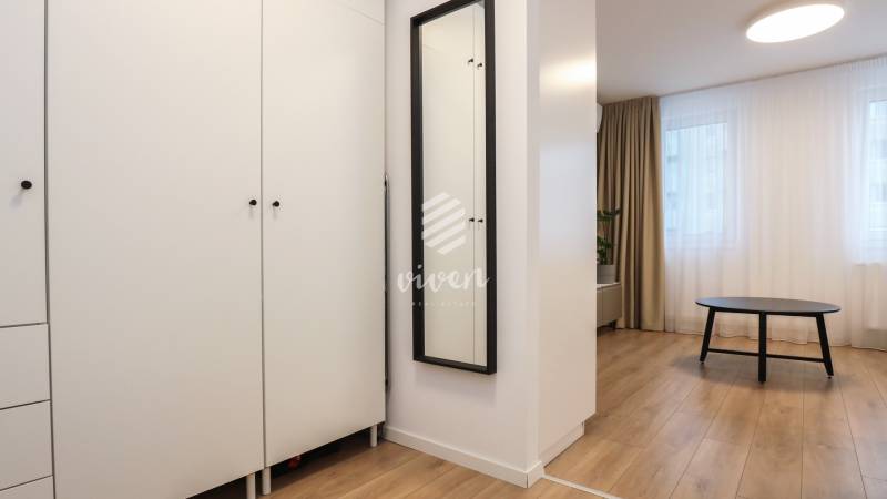 Bútor egy egyszobás lakásban fa dekor padlóval és fekete asztallal.