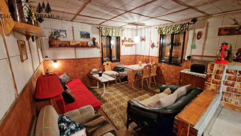 Rusztikus belső tér a házikóban kanapékkal, fa dekorációval és díszítésekkel, otthonos hangulatban.