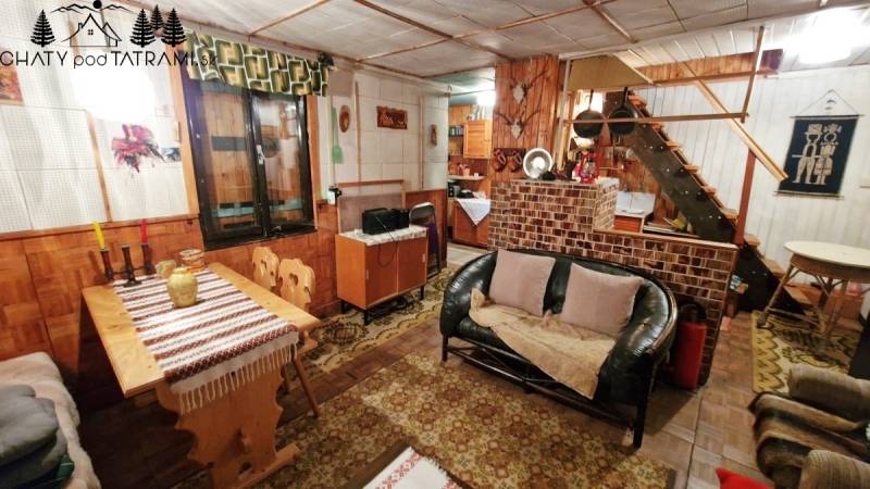 A ház belseje kanapéval, fa dekorációjú padlóval, étkezőasztallal és lépcsővel.