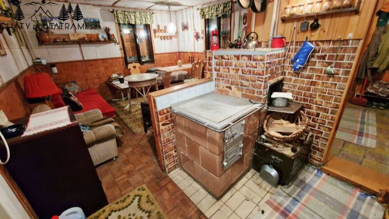 Egy hagyományos téglakályhával, fa dekorációjú padlóval és kényelmes ülőhellyel rendelkező házikó belső tere.