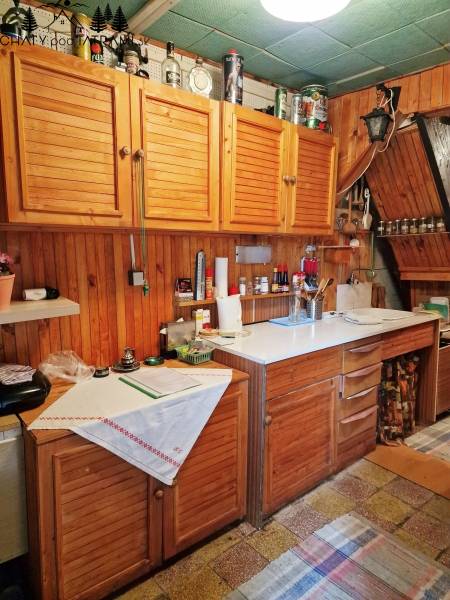 Konyha faházban fa szekrényekkel és fehér munkalappal, otthonos légkör.