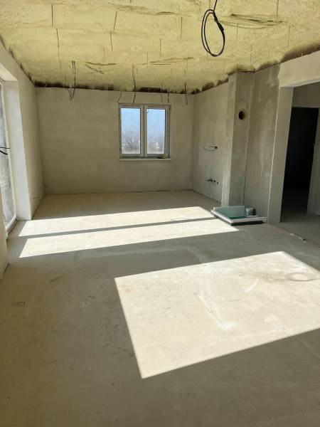 Tágas szoba egy családi házban a Vyšná Šebastová utcán, nyers vakolattal és kábelekkel.