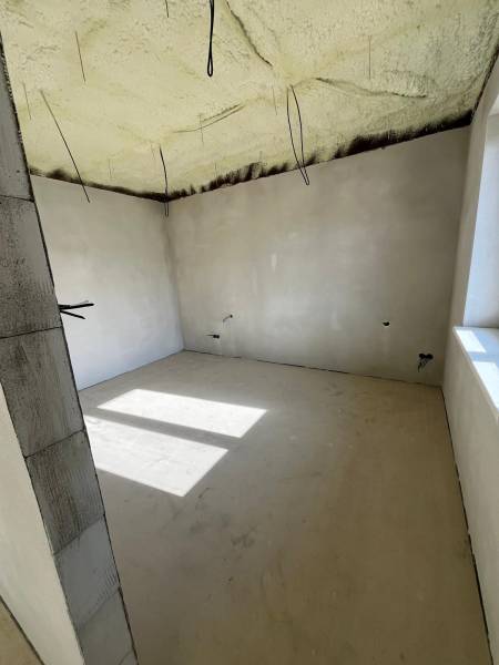 Családi ház szigetelt mennyezete a Vyšná Šebastová utcában. Világos szoba nagy ablakkal.