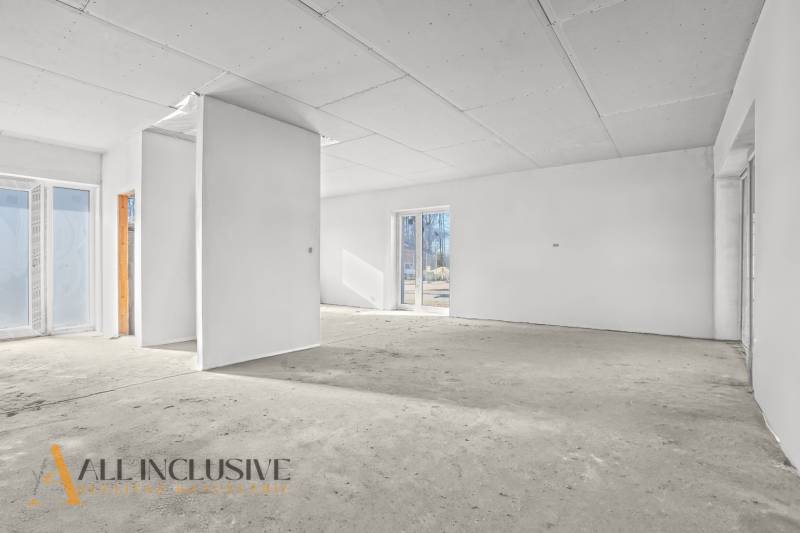 Üres belső tér egy családi házban fehér falakkal és nagy ablakokkal.