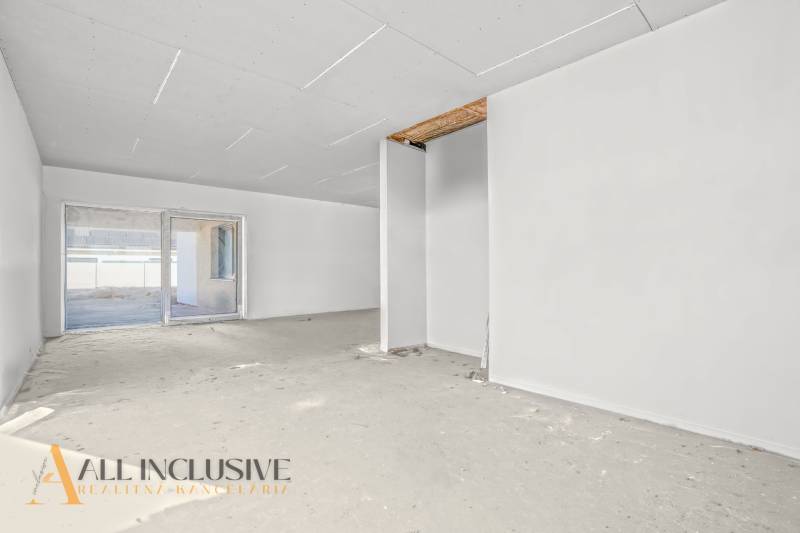 Tágas szoba egy családi házban befejezetlen padlóval és nagy ablakkal.