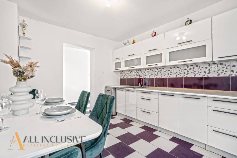 Családi ház konyhája beépített készülékekkel és geometrikus csempével.