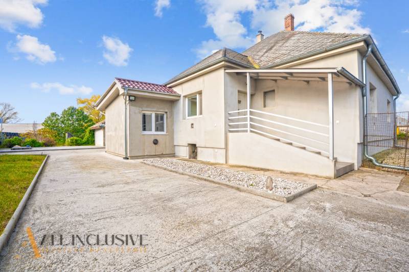 Családi ház Nagykeszin ferde tetővel és kövezett udvarral.