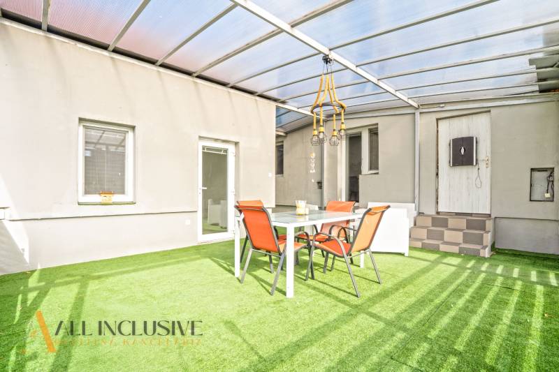 A Veľké Kosihy-i családi ház terasza műfűvel és kerti bútorokkal.