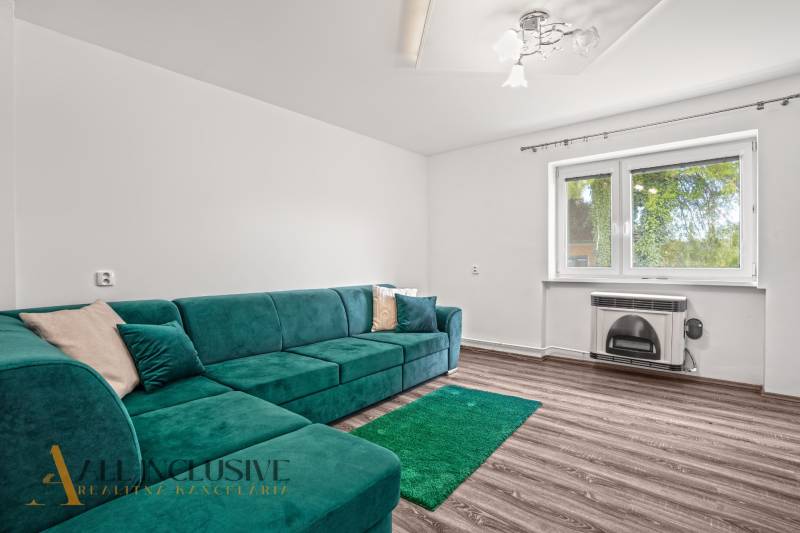 Nappali egy családi házban türkiz kanapéval és fa dekorációjú padlóval.