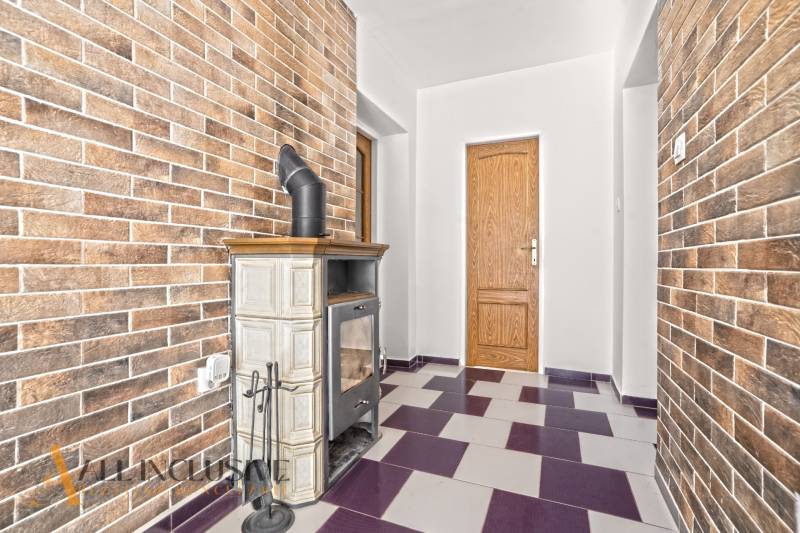 Családi ház belső tere cserépkályhával és téglafalakkal.
