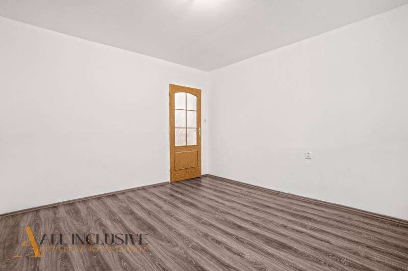 Fehér belső tér fa dekorációjú ajtóval és padlóval egy családi házban.