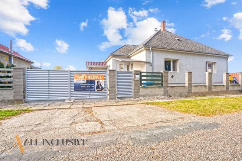 Eladó családi ház Nagycsalomján, fehér homlokzati burkolat, széles kapu.