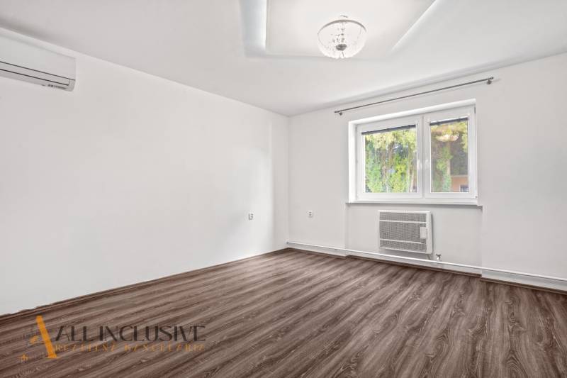 Egy családi ház szobája fa dekoros padlóval és fehér falakkal.