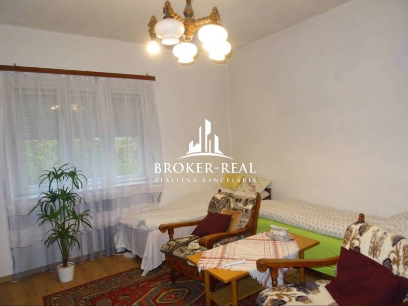 Kényelmes szoba családi házban, fotelekkel, ágyakkal és fa dekorációjú padlóval.