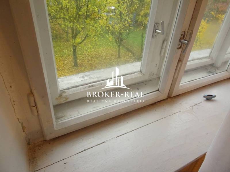 Kilátás egy családi ház ablakából egy őszi kertre és egy fára.