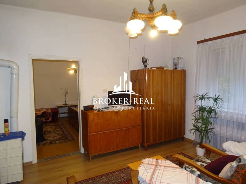 Nappali egy családi házban fa szekrényekkel, kanapéval és virággal.