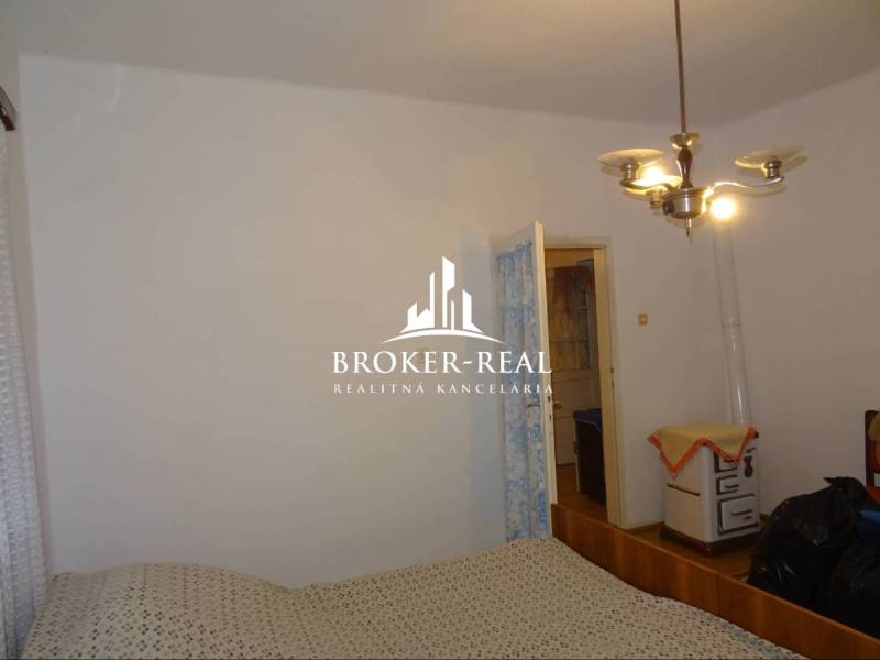 Családi ház hálószobája egyszerű berendezéssel és retro fűtéssel.