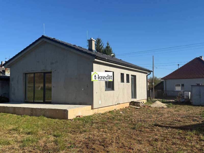 Családi ház Tesárske Mlyňany-ban vakolatlan homlokzattal és beton terasszal.