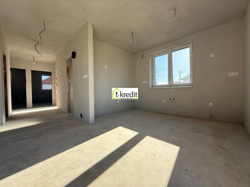 Családi ház belső tere befejezetlen falakkal és ablakkal, fa dekorációjú padlóval.