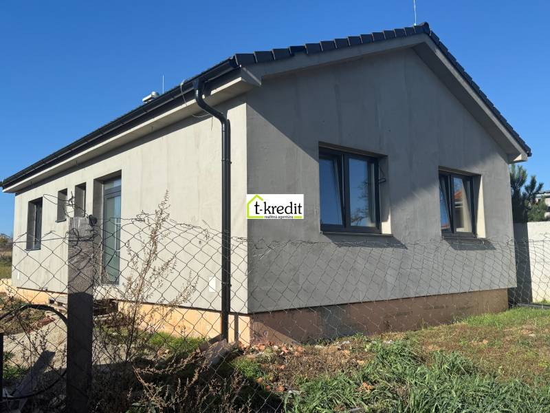 Családi ház Tesárske Mlyňany-ban szürke homlokzattal és ablakokkal, kerítéshálóval körbekerítve.