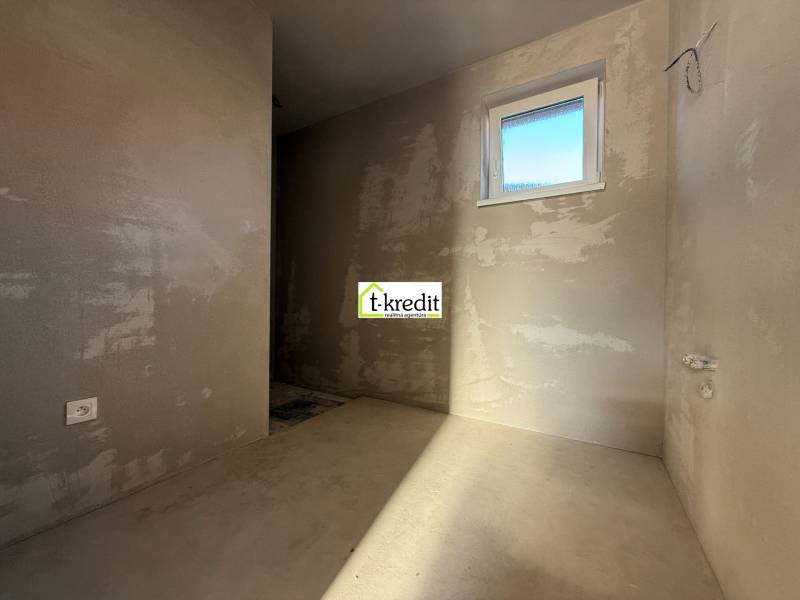 Csupasz falak, ablak és aljzat egy családi ház belsejében; készen áll a további fejlesztésekre.