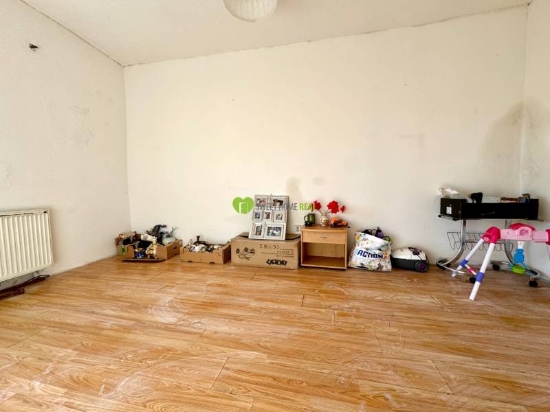 Egy szoba családi házban, fa dekoros padlóval és különböző tárgyakkal a falnál.