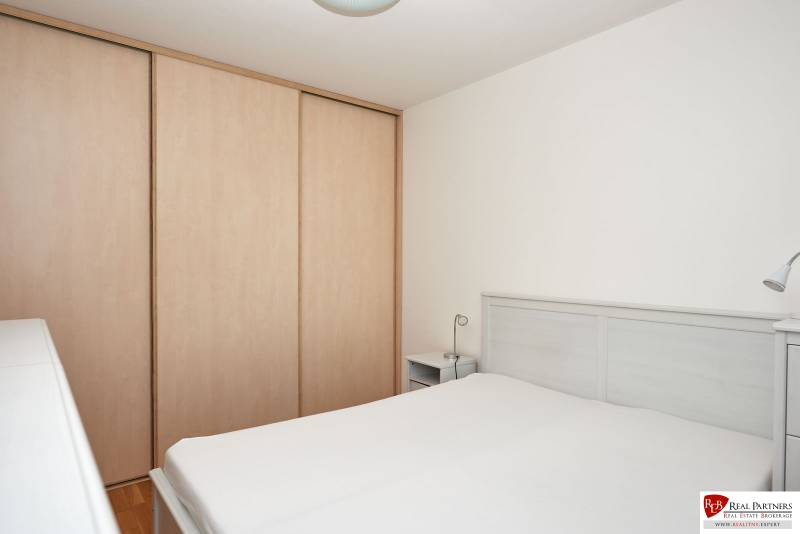 Hálószoba egy kétszobás lakásban ággyal, szekrénnyel és fehér falakkal.