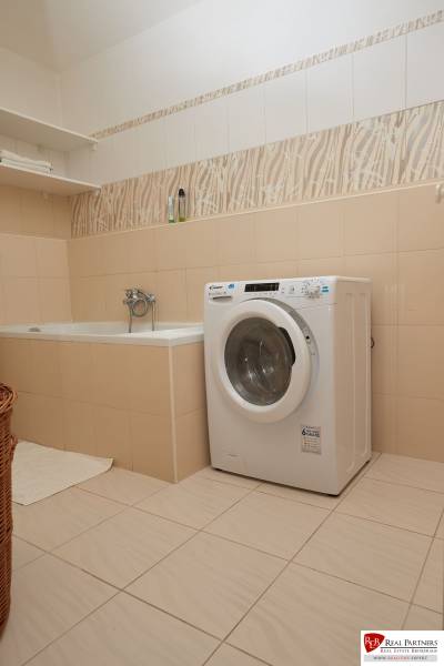 Fürdőszoba káddal, mosógéppel és polccal egy kétszobás lakásban.