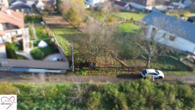 Földterületek - lakóövezet az M.H. Chvoteková utcában Dolná Krupában, zöldövezettel és parkoló autóval.