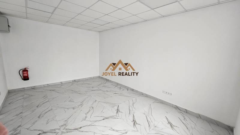 Márványpadlós üzlethelyiség tűzoltó készülékkel a falnál.